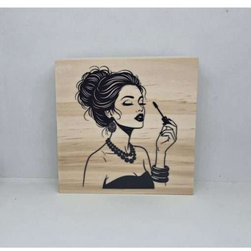 Glamorous Lady Shelf Sitter featuring a black illustration of an elegant woman applying makeup on a natural pine wood block displayed on a dressing table.