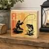 Rustic Fishing Desk Sitter featuring a fisherman in a boat casting toward a leaping fish, with colourful lettering on a natural wooden block.