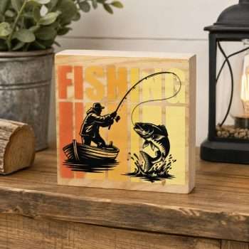 Rustic Fishing Desk Sitter featuring a fisherman in a boat casting toward a leaping fish, with colourful lettering on a natural wooden block.